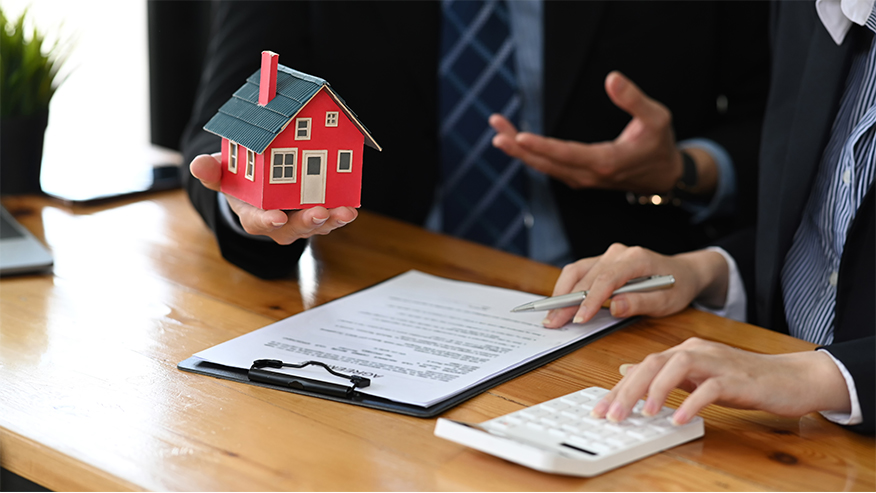Asesoría inmobiliaria profesional ofreciendo servicios para casa llave en mano con una maqueta de vivienda en la mano